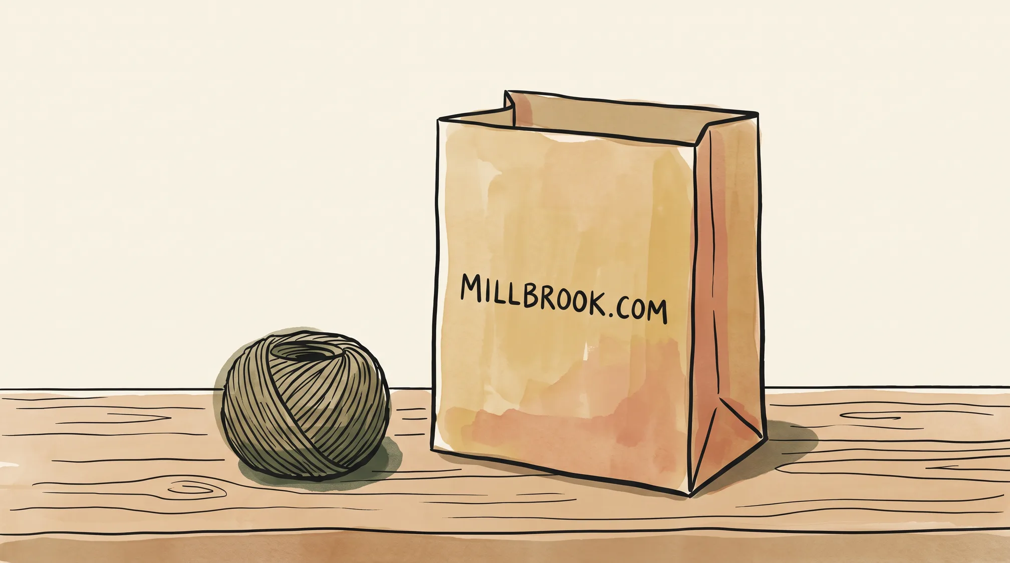 A brown paper shopping bag on a wooden counter printed with the words MILLBROOK.COM, a ball of twine beside it.